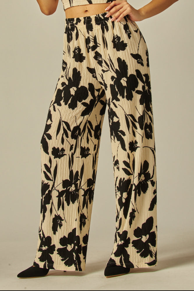 Woman wearing a black floral jumpsuit on a beige background